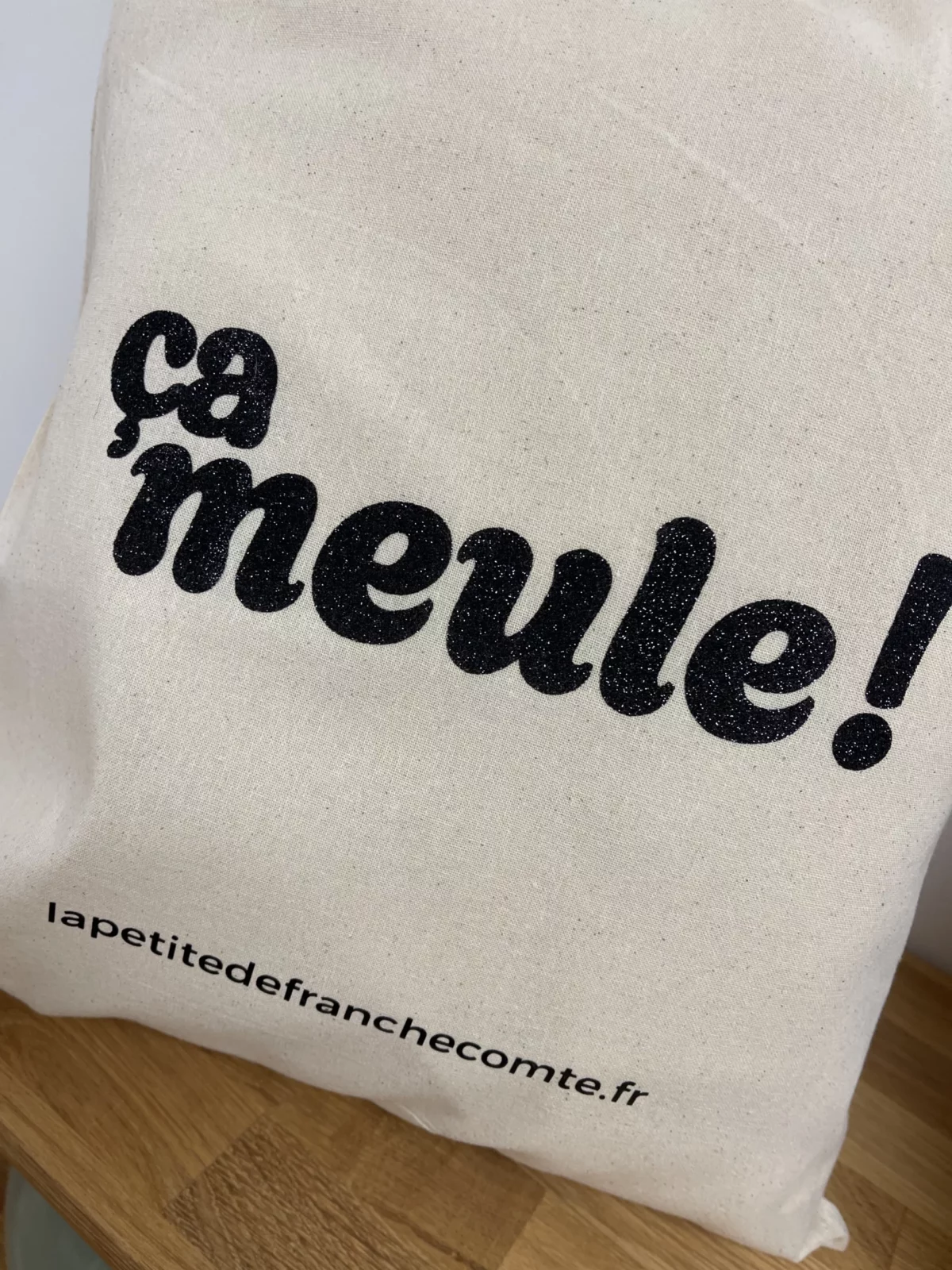 Tote-bag couleur noir, artisanal en coton naturel certifié Oeko-Tex, fabriqué en Franche-Comté avec l'expression "ça meule", sac écologique et original.